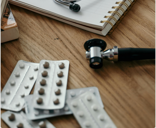 Schreibtisch beim Arzt mit unterschiedlichen Pillenpackungen auf dem Tisch