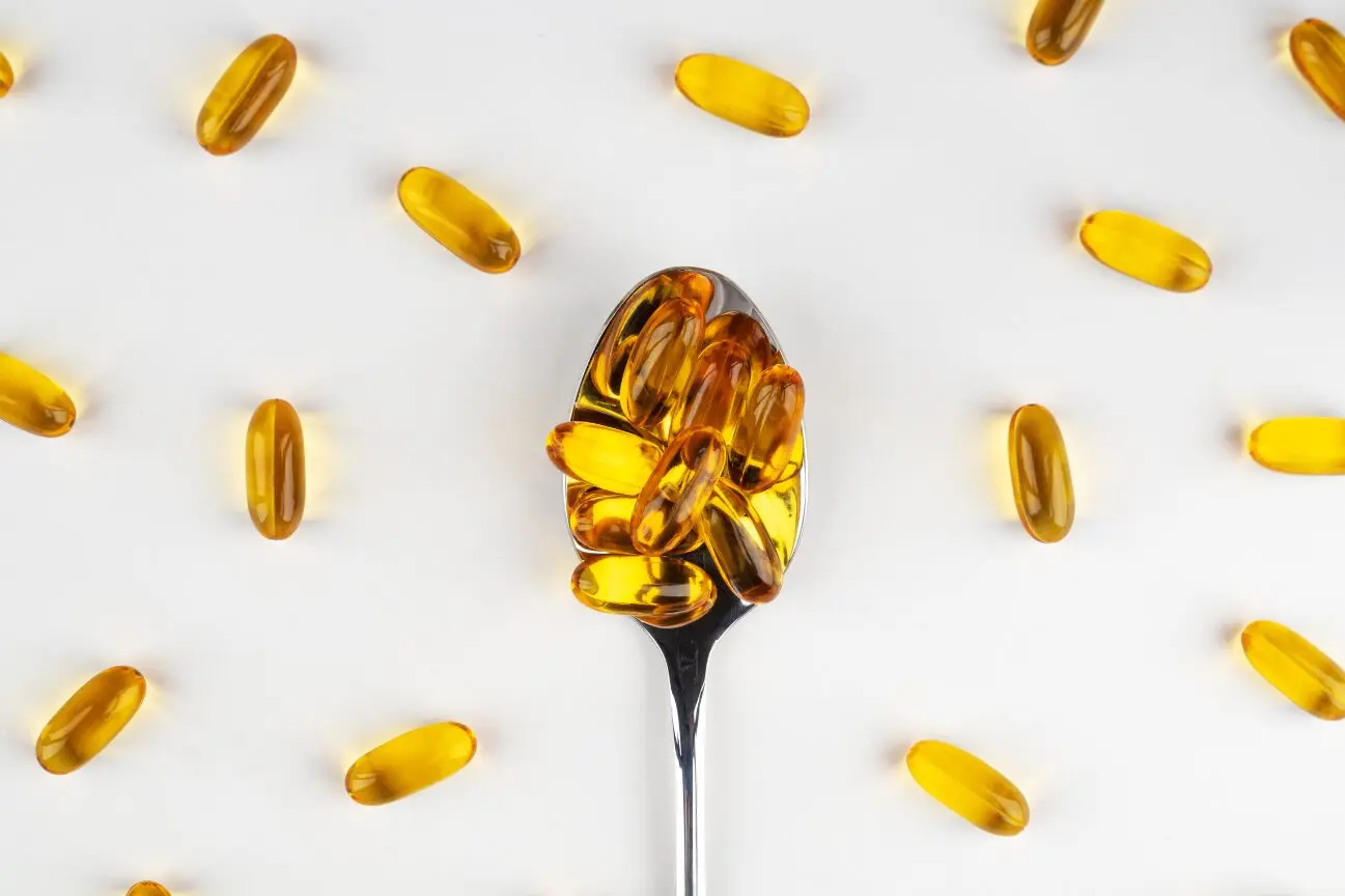 Omega 3 Kapseln bei Omega 3 Mangel auf Löffel vor weißem Hintergrund